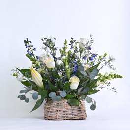 White and blue floral arrangement in a woven basket