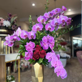 Pink orchids and red roses in a gold vase
