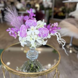 Purple and white orchid arrangement in a glass vase