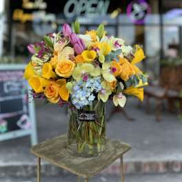 Bright mixed bouquet in a clear glass vase on a small table