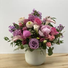 Mixed pink and purple flower arrangement in a white vase