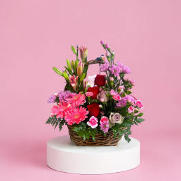 Basket arrangement of pink and red flowers with lilies and roses
