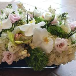Low floral centerpiece with white orchids, hydrangeas, and pale pink blooms