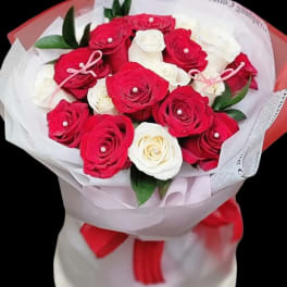 Bouquet of red and white roses wrapped in paper with a red ribbon