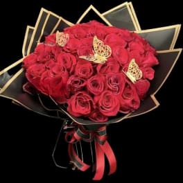 Bouquet of red roses wrapped in black paper with gold trim