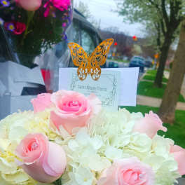 Pink roses in a white box with pale hydrangeas and a butterfly card topper