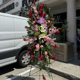 Tall standing floral spray with pink, red, and white blooms on an easel
