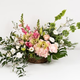 Basket arrangement of pink and white flowers with tall green spikes