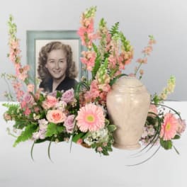 Pink floral arrangement with a framed portrait and urn