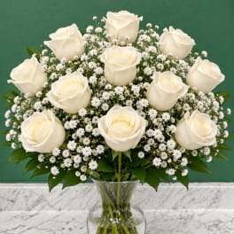 White roses and baby's breath in a clear glass vase