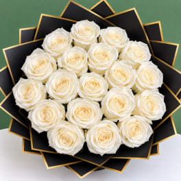 Bouquet of white roses wrapped in black paper with gold trim