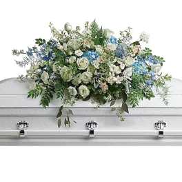 White and blue floral casket spray on a white casket