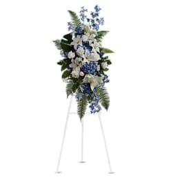 Standing floral spray with white lilies and blue flowers on an easel