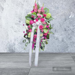 Standing floral spray with pink roses and a white ribbon bow