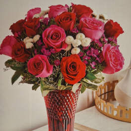 Bouquet of red and pink roses in a red glass vase