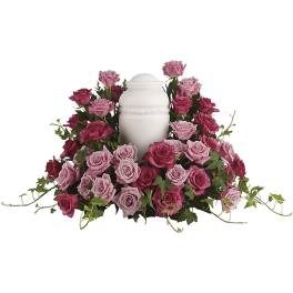 Pink and magenta roses arranged around a white urn