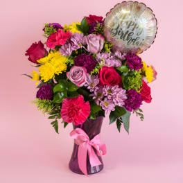 Mixed bouquet in a purple vase with a birthday balloon
