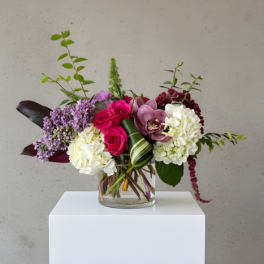 Mixed bouquet of pink, white, and purple flowers in a clear glass vase