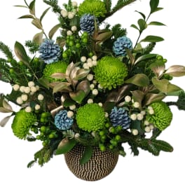 Green chrysanthemum arrangement with blue pinecones in a gold vase