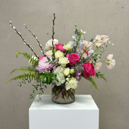 Mixed pink and white flowers arranged in a clear glass vase