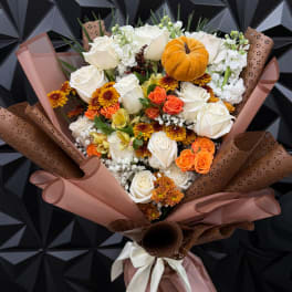 Bouquet of white roses and orange flowers with a small pumpkin accent