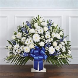 White and blue floral spray with a blue ribbon on a stand