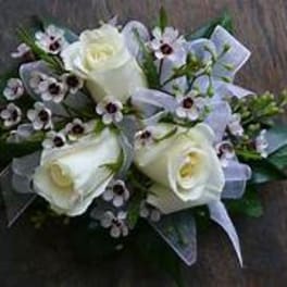 White roses and small purple flowers arranged with a ribbon