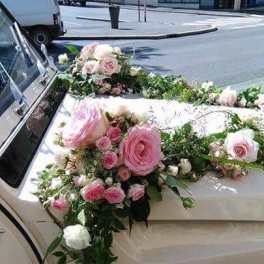 Pink and white floral arrangement draped over a car hood
