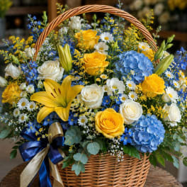 Basket arrangement of yellow and white roses with blue hydrangeas and lilies