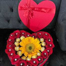 Heart-shaped gift box with red roses, a sunflower, and chocolates