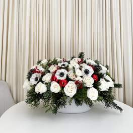 White rose arrangement with red accents in a white bowl vase