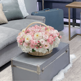 Basket of pink and white flowers with a woven handle