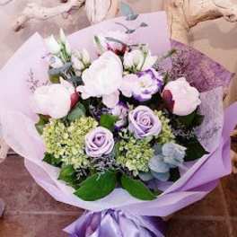 Lavender and white bouquet with roses and hydrangeas wrapped in purple paper