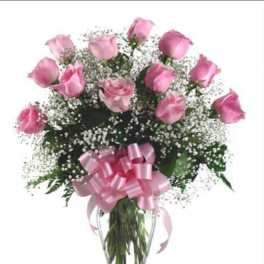 Pink roses in a clear glass vase with a pink ribbon bow