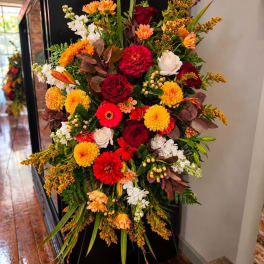 Large arrangement of red, orange, yellow, and white flowers in a black stand