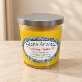Yellow candle in a glass jar with a silver lid and printed label
