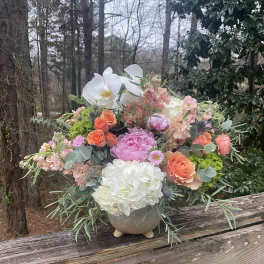 Mixed bouquet in a stone vase with white orchids and pink, peach, and white blooms
