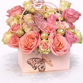 Pink and cream roses in a pale pink gift box with butterfly decorations