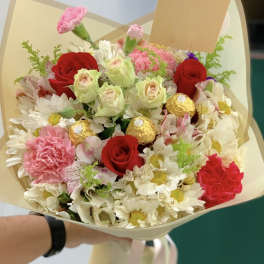 Bouquet of red roses, pink carnations, and white daisies with gold chocolates