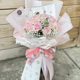 Pink rose bouquet wrapped in pale paper with a ribbon bow