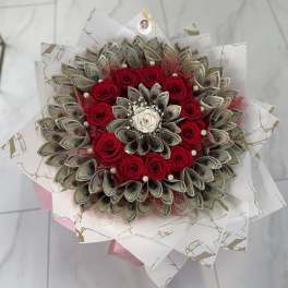 Bouquet of red roses and folded dollar bills wrapped in white paper