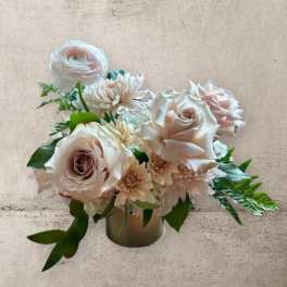Blush roses and pale daisies arranged in a small vase