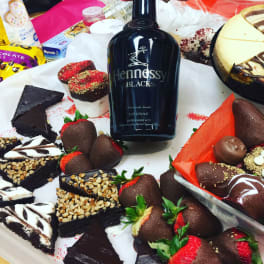 Assorted chocolate-covered strawberries and desserts around a Hennessy Black bottle