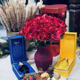 Red rose bouquet in a vase with chocolate-covered strawberries and gift boxes
