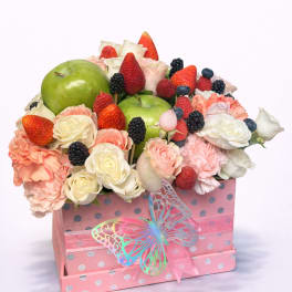 Fruit and flower arrangement in a pink gift box with a butterfly ribbon