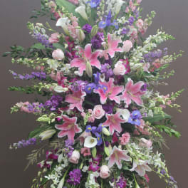 Large standing floral spray with pink lilies, white calla lilies, and purple blooms