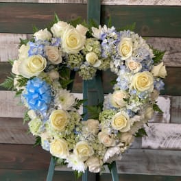 Heart-shaped floral wreath with cream roses and blue hydrangeas on an easel