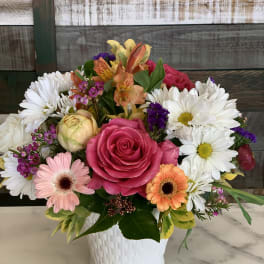 Mixed bouquet with pink roses, daisies, and orange alstroemeria in a white vase