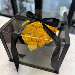 Yellow roses in a clear square box tied with a black ribbon