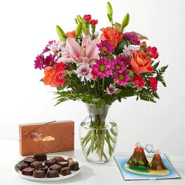 Mixed bouquet in a glass vase with chocolates and a volcano card